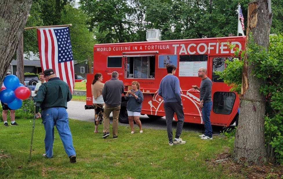 Red food truck with several people standing in front of it